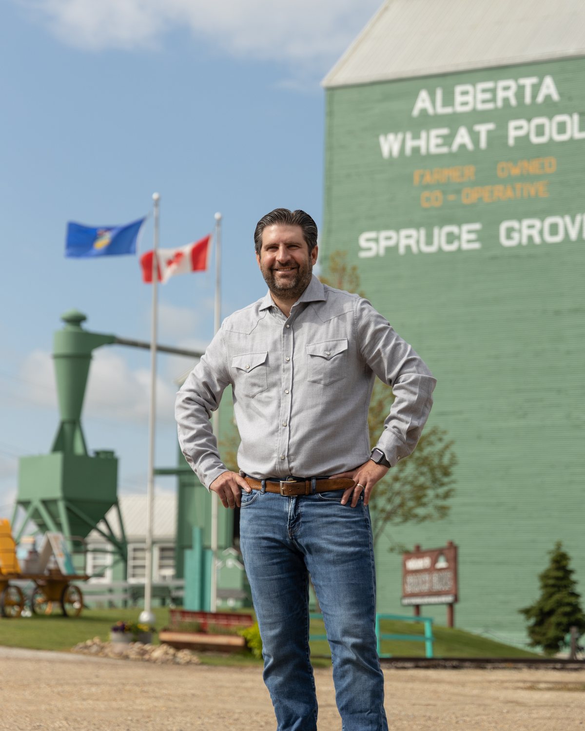 Ben Lotery outside the Alberta Wheat Pool elevator in Spruce Grove, beneath the Alberta and Canadian flags